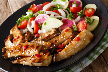 Spicy grilled king oyster mushrooms and a salad of radish and tomato close-up. horizontal