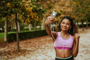 Young sporty hispanic woman taking selfie outside.