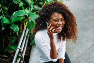 Portrait of smiling curly hair woman talking on phone. - Powered by Adobe