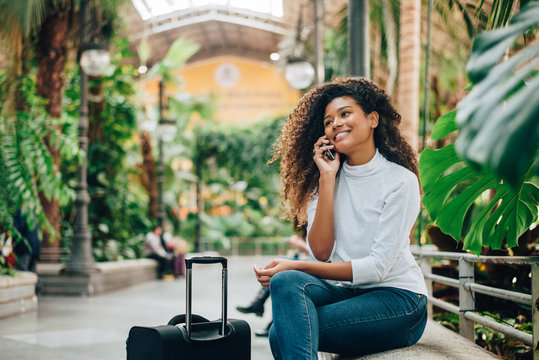 Young woman traveler with luggage talking on phone.