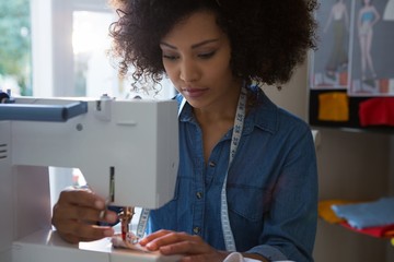 Female fashion designer stitching cloth in sewing machine