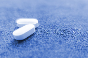 Fototapeta na wymiar White pills on blue background