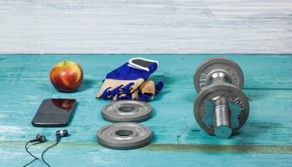 Sport items bottle, dumbbells, gloves on the sport flooring