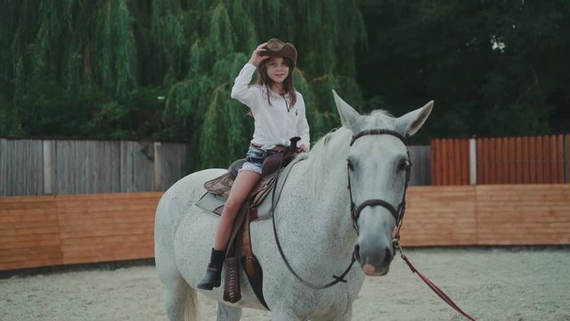 Pretty girl sitting on the friendly horse and caresses it in 4K