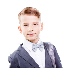 Serious young male student of primary school isolated on white background. Calm and confident schoolboy in suit with backpack on his shoulder