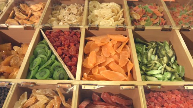 Dried fruits and berries.
Smooth movement of the camera along boxes with dried fruits: peach, pear dried, kiwi slices, cherry tomatoes, dried mango, pomelo, bananas.