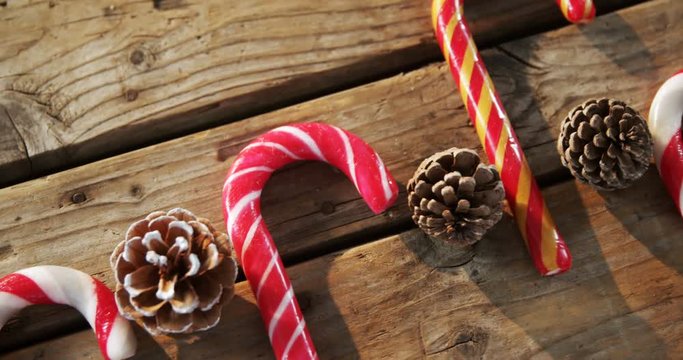 Candy cane with pine cone on wooden table 