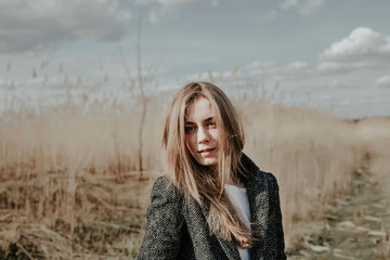 Pretty and young european woman with face covered  by her blonde hair looking at camera. Girl...