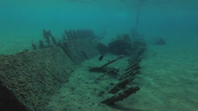 A wreck wooden fishing boat lies in shallow water, on a sandy bottom in the port, Red sea, Egypt
