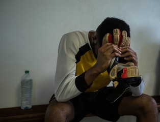 Football player sitting on bench in changing room
