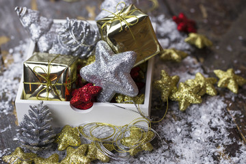 Christmas ornaments of red, gold and silver color are spread out on an old wooden background and in a box.