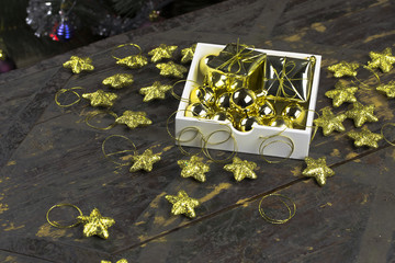 Christmas ornaments of gold color in a box on an old wooden background.