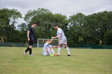 Football player assisting his friend to get up