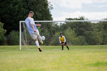 Soccer player kicking ball towards goal post