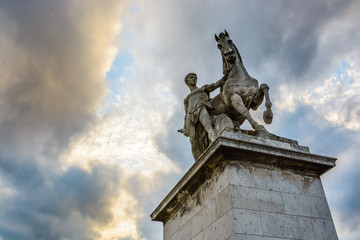 Fototapeta na wymiar View from below of the equestrian statue of a roman warrior by Louis-Joseph Daumas located on the left bank of the Iena bridge in Paris under a heavy cloudy sky.