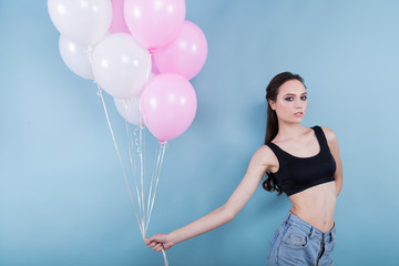 Brunette girl in a black top, holds nine balloons