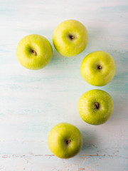 Green apples forming question mark on turquoise white table. Flat lay