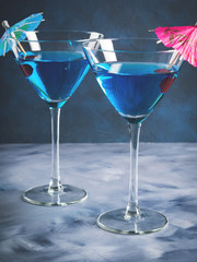 Blue cocktail drink in martini glass with umbrella and cherry