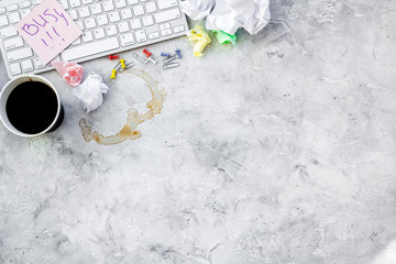 Clutter in office. Desk covered with crumpled paper and coffee stains. Grey background top view copyspace