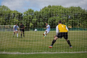 Soccer player kicking ball towards goal post