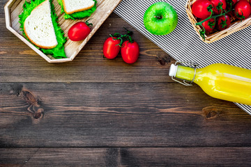 What bring for a picnic. Sanwiches, fruits, vegetables, juice on dark wooden background top view copyspace