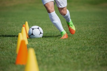 Soccer player dribbling through cones