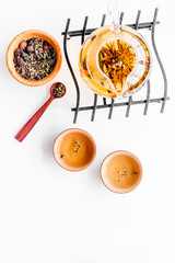 Tea ceremony concept. Tea pot, cups or bowls, dry tea leaves on white background top view copyspace