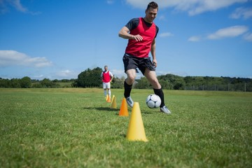 Soccer player dribbling through cones