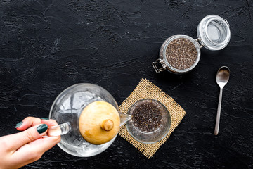 Hand brew chia seeds. Jar with seeds, scoop, bowl, tea pot with hot water. Black background top view copyspace