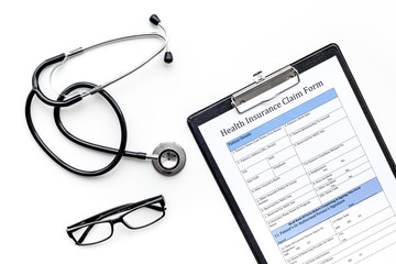 Health insurance for reception at the doctor. Document, stethoscope, pad, glasses on white background top view