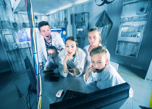 Husband with wife and children are solving puzzles on computer