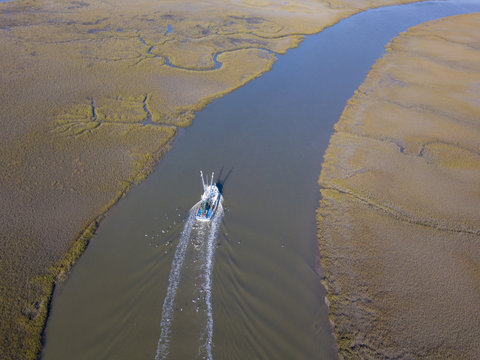 Aerial view of shrimp boat coming into port on coastal delta.