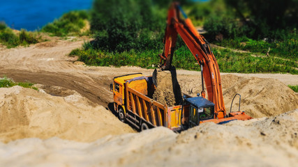 Excavator loading sand into dumper truck