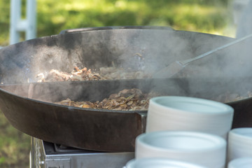 Preparing a goulash in a big wok at a festival outdoors