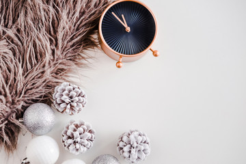White Christmas background. Faux fur, rose gold clock, frosty pine cones, silver and white colored decoration balls. Minimalistic style. Copyspace for text, overhead, horizontal