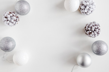 White Christmas background. Frosty pine cones, white, glitter, silver colored decoration balls. Minimalist style. Copyspace for text, overhead, horizontal