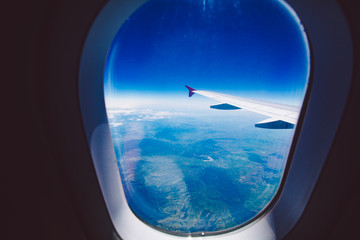 Naklejka na ściany i meble Looking through window aircraft during flight in wing blue sky.