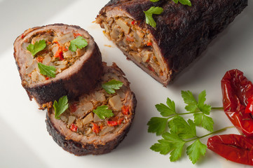 Stuffed meat with parsley and sun-dried tomatoes in olive oil on a white plate