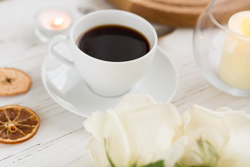 Coffee for breakfast or lunch with decorations, candles and flowers. white roses on the table and cup of coffee