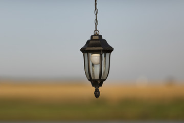 Street lamp with a white bulb under glass hanging on a chain