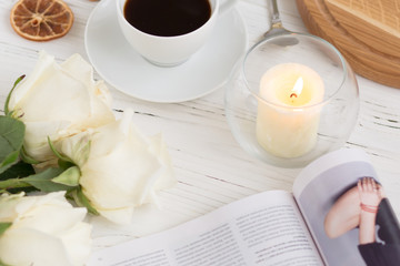 Coffee for breakfast or lunch with decorations, candles and flowers. white roses on the table and cup of coffee