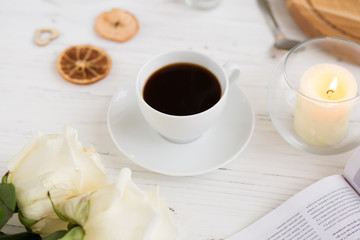 Coffee for breakfast or lunch with decorations, candles and flowers. white roses on the table and cup of coffee