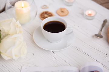 Coffee for breakfast or lunch with decorations, candles and flowers. white roses on the table and cup of coffee