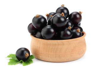 black currant in wooden bowl with green leaf isolated on white background