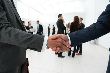 closeup of handshake of business partners on the background of business team
