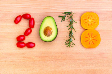 Year 2018 made of vegetables, herbs and fruits on wooden background. © volgariver