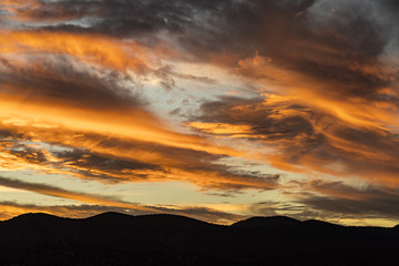 beautiful striped clouds over silhouetted mountains during sunset