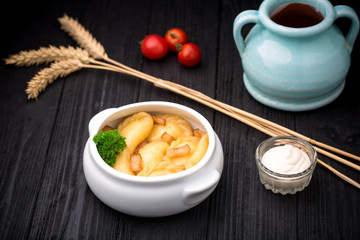 Dumplings with potatoes and cracknel on black rustic wooden background