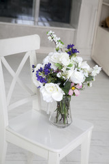 Fototapeta na wymiar the Bouquet of artificial roses, phlox and bells on a table in a vase, as an interior decoration