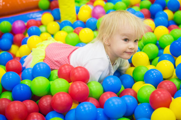 Fototapeta na wymiar THE BABY IS PLAYING IN COLORED BALLS